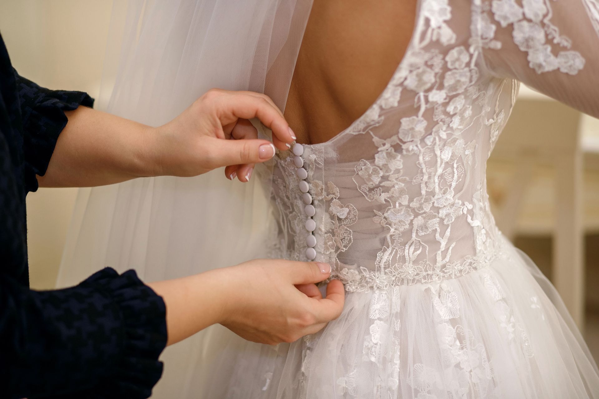 Hands adjusting white lace wedding dress details